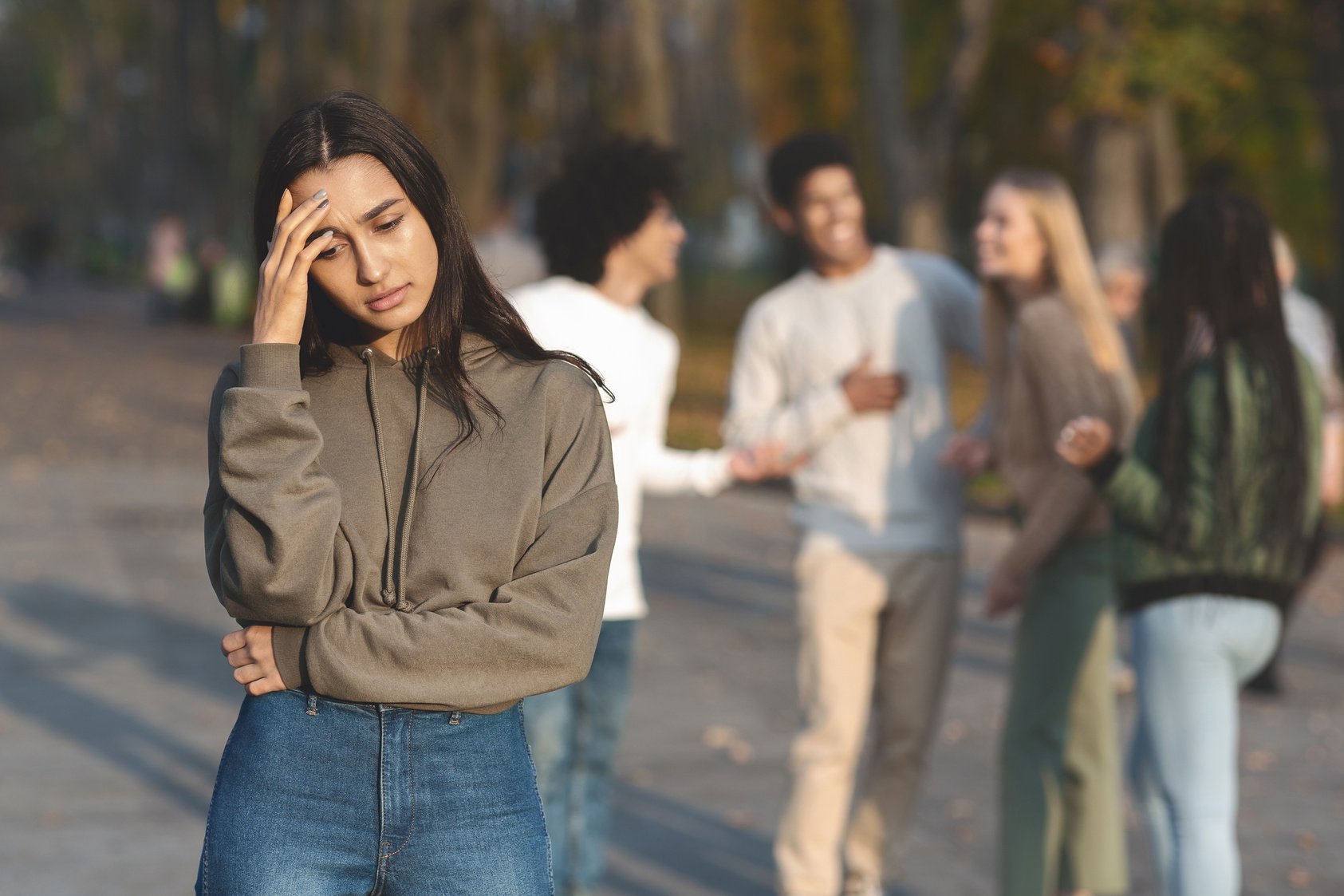 Upset girl staying apart from group of teenagers